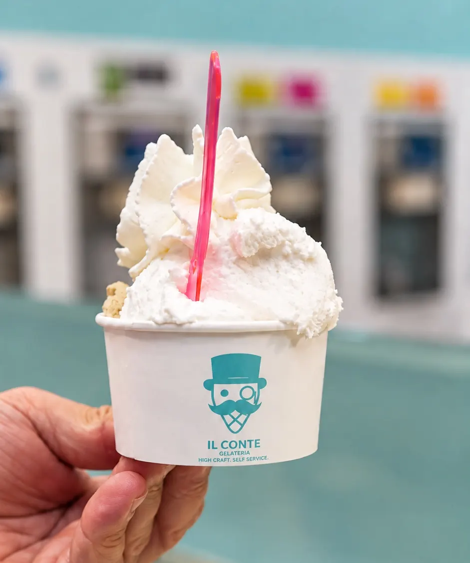 Coppetta col logo del Conte e la panna, davanti alle macchine del self service
